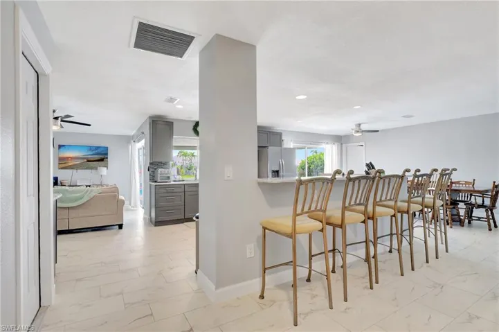 Kitchen with light tile patterned floors, gray cabinetry, stainless steel refrigerator with ice dispenser, and ceiling fan