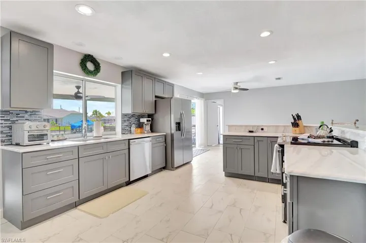 Kitchen with ceiling fan, sink, appliances with stainless steel finishes, light tile patterned floors, and gray cabinetry
