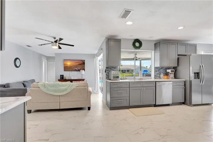 Kitchen with decorative backsplash, ceiling fan, stainless steel appliances, and gray cabinetry
