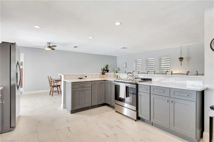 Kitchen featuring gray cabinetry, ceiling fan, kitchen peninsula, and stainless steel appliances
