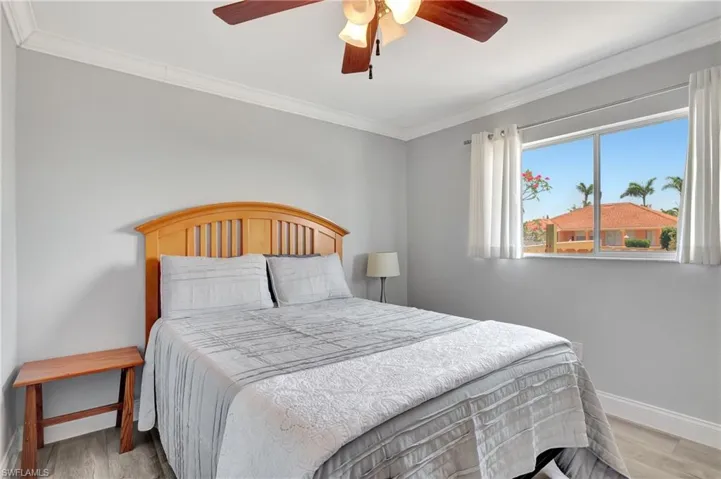 Bedroom featuring light hardwood / wood-style flooring, ceiling fan, and crown molding