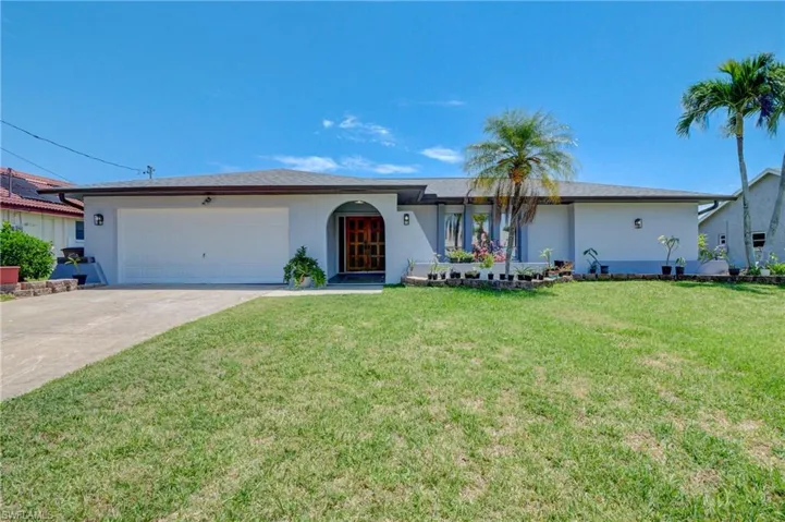Single story home with a garage and a front lawn