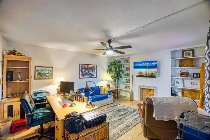 Tiled office featuring a textured ceiling, built in features, a ceiling fan, and a fireplace