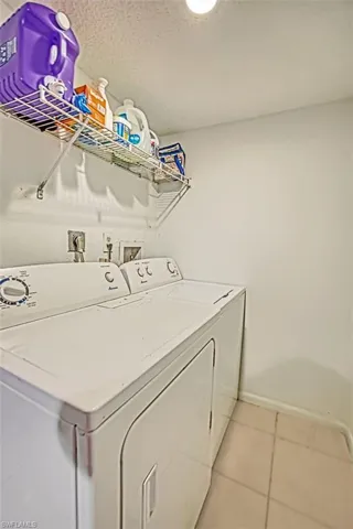 Laundry area featuring light tile patterned flooring and washing machine and clothes dryer