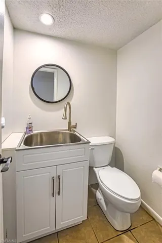Half bath featuring a textured ceiling, vanity, and light tile patterned floors