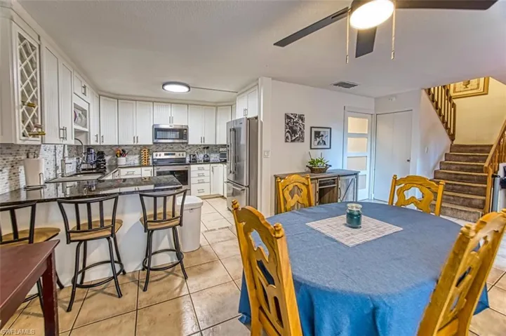 Dining space with stairs, light tile patterned floors, and ceiling fan