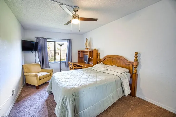 Carpeted bedroom with ceiling fan, a textured ceiling, and a textured wall