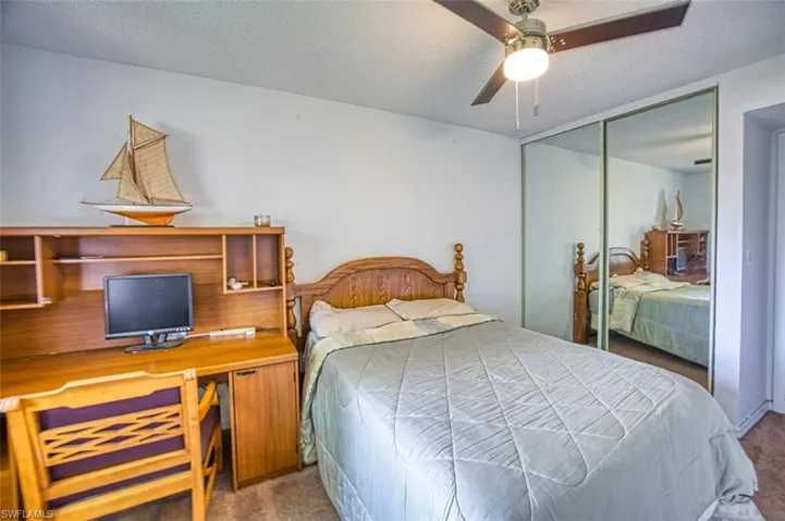 Carpeted bedroom with a textured ceiling, ceiling fan, and a closet