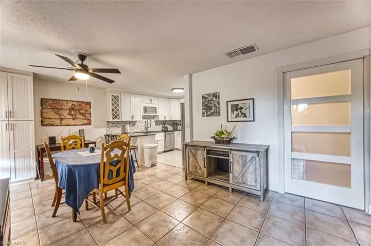 Dining area with a textured ceiling, built in features, ceiling fan, and light tile patterned floors