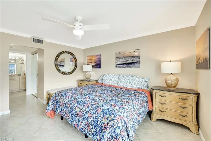 Bedroom featuring crown molding, ensuite bathroom, a ceiling fan, light tile patterned flooring, and a closet