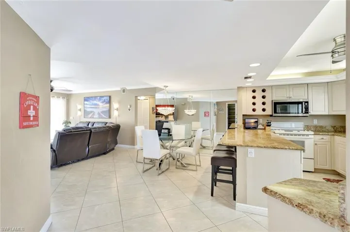 Kitchen featuring ceiling fan, open floor plan, white electric stove, a breakfast bar area, and recessed lighting