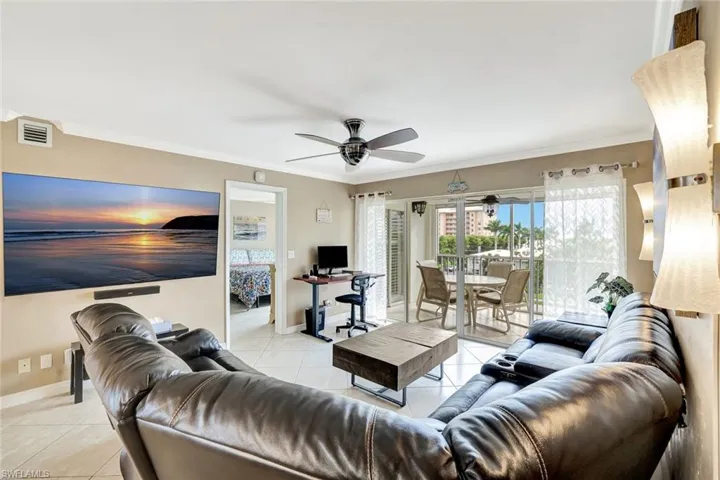 Living room featuring light tile patterned flooring, crown molding, and an office area