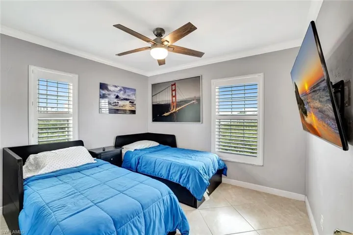 Bedroom with crown molding, light tile patterned flooring, and ceiling fan