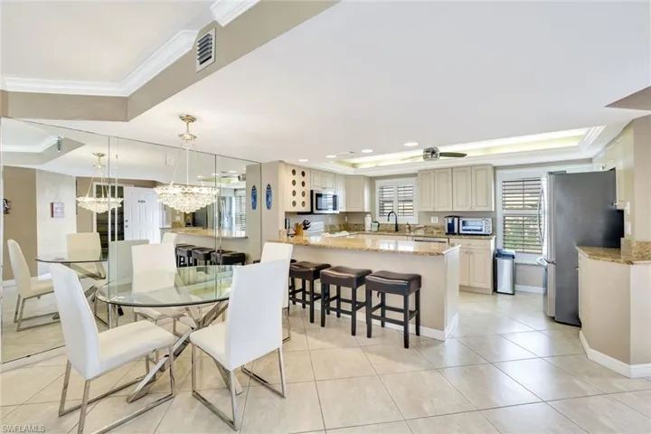 Dining room with crown molding, light tile patterned floors, a raised ceiling, and a chandelier