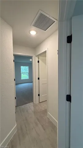 Hallway featuring wood-finish flooring, white walls, recessed ceiling lighting, and crisp white trim