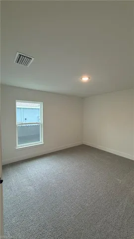 Carpeted room with a single window, recessed lighting, and white baseboards