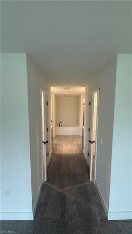 Hallway with carpeted flooring, white walls, and recessed lighting