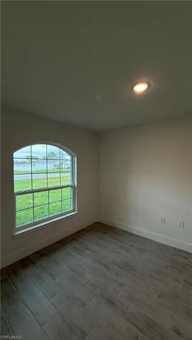 Room featuring a vaulted ceiling with a recessed light fixture, a large arched window, and wood-finish tile flooring