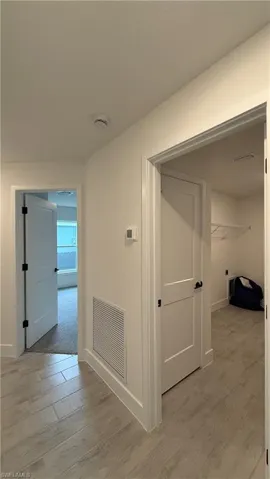 Hallway with light wood-finish flooring, white walls, and white trim