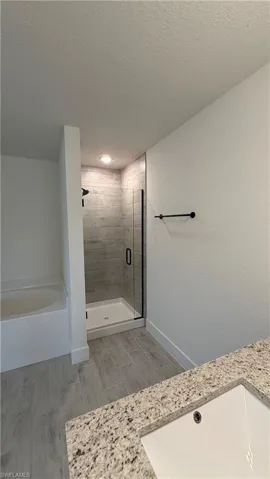 Bathroom featuring a walk-in shower with gray tile surround and black-framed glass enclosure