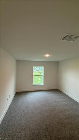 Neutral-toned room featuring a single window, recessed lighting, white walls, white baseboards, and dark gray carpeting