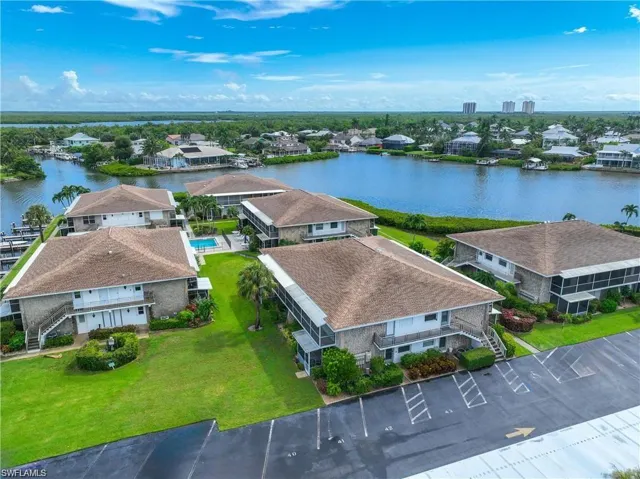 Aerial view of the waterfront condominium community with landscaped grounds, community pool, and surrounding waterways.