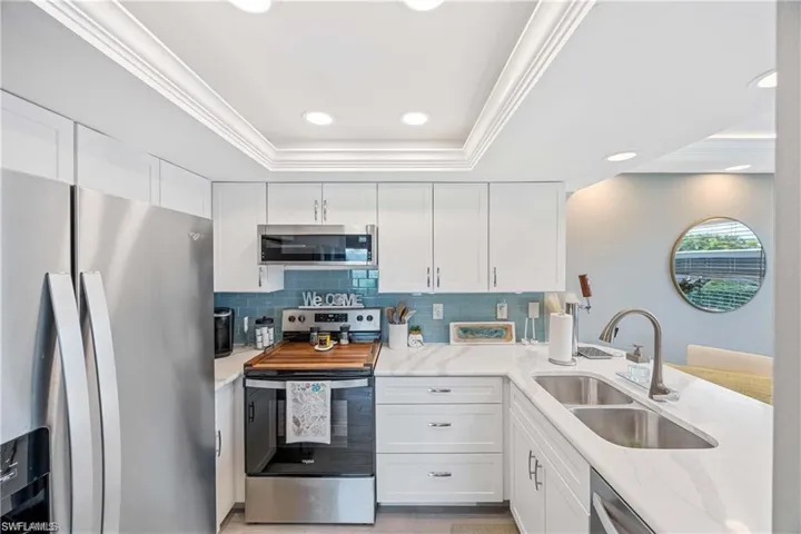 Bright kitchen with white cabinetry, stainless steel appliances, quartz-style countertops, and recessed lighting.