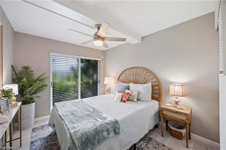 bedroom with abundant natural light, ceiling fan, and large window overlooking the landscaped grounds.