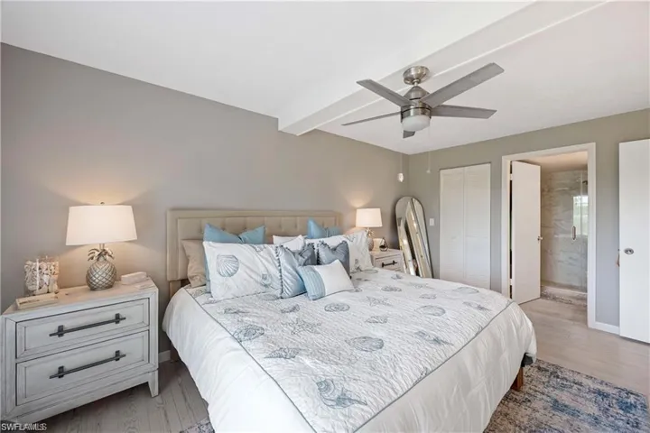 bedroom featuring an en-suite bathroom, ceiling fan, and coastal-inspired finishes.