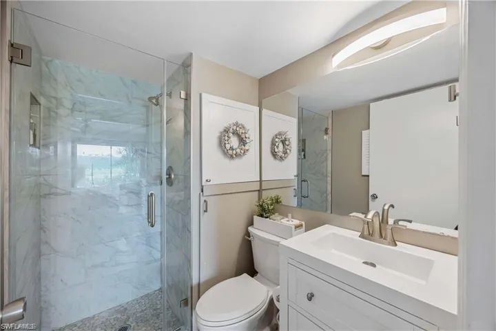Primary bathroom featuring a glass-enclosed walk-in shower, modern vanity, and additional storage cabinetry.