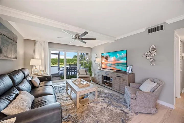 Spacious living room with sliding glass doors opening to the screened lanai and outdoor living area.