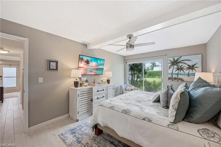 bedroom with large window, natural light, and views of the landscaped community grounds.
