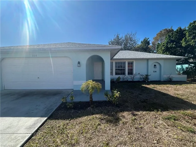 Single story home featuring a garage, stucco siding, driveway, a front lawn, and roof with shingles