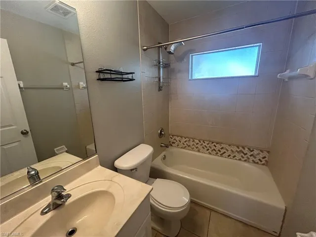 Bathroom featuring vanity, bathtub / shower combination, tile patterned floors, and a textured wall