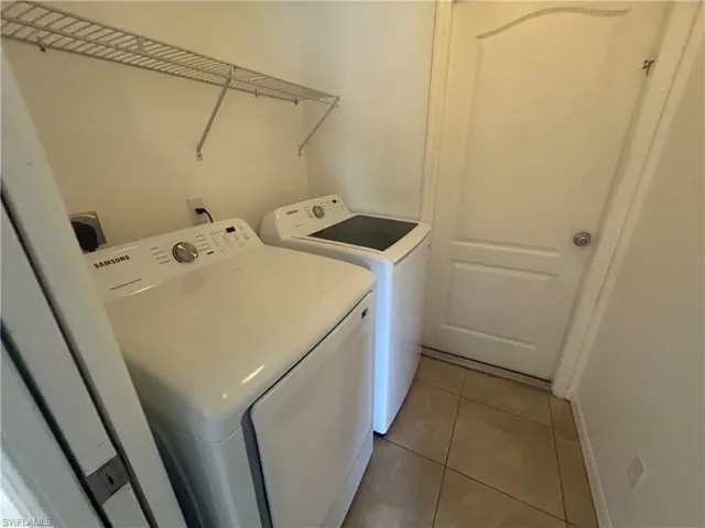 Laundry area featuring light tile patterned floors and independent washer and dryer