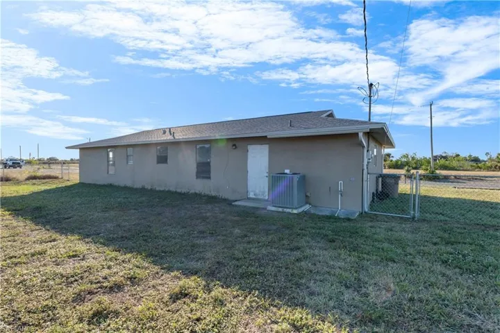 Rear view of house with a yard and cooling unit
