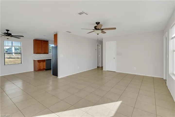 Unfurnished living room with light tile patterned floors and ceiling fan