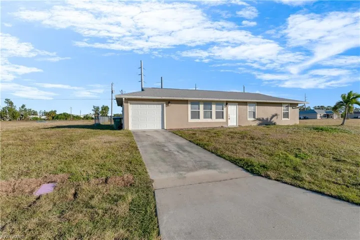 Ranch-style home with a garage and a front lawn