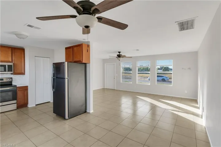 Kitchen featuring decorative backsplash, light tile patterned floors, stainless steel appliances, and ceiling fan