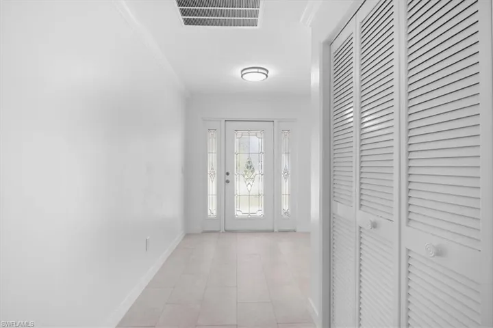 Foyer featuring crown molding and light tile patterned floors