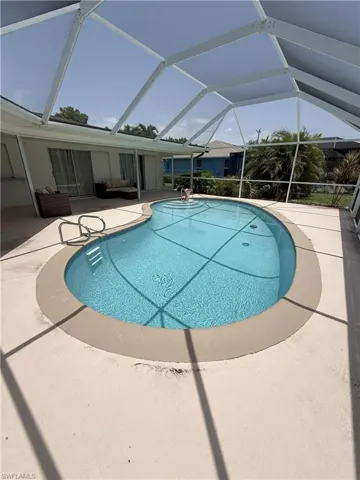 Outdoor pool with a patio, a sunroom, and glass enclosure