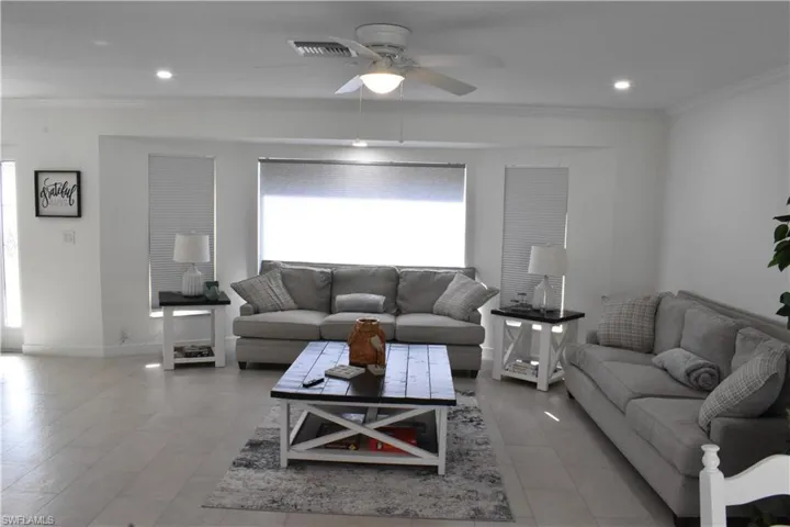 Living room with ornamental molding, a ceiling fan, recessed lighting, and light tile patterned floors