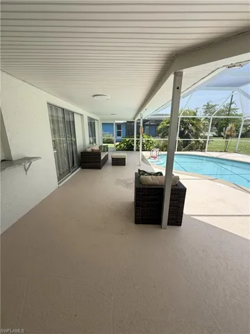 View of patio featuring a sunroom, an outdoor pool, glass enclosure, and an outdoor hangout area
