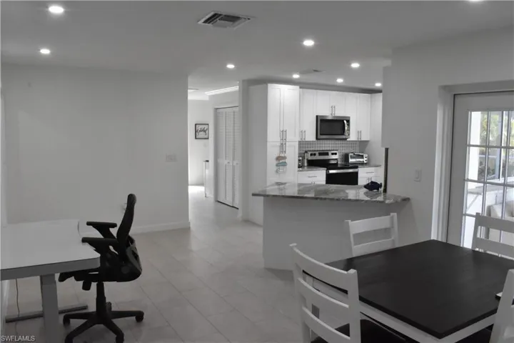 Kitchen with stainless steel appliances, dark stone countertops, white cabinetry, recessed lighting, and decorative backsplash