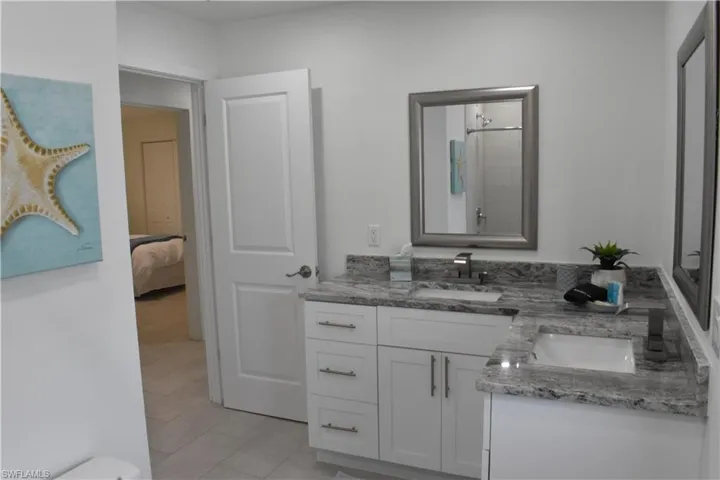 Full bathroom with double vanity, light tile patterned floors, a shower, and ensuite bath