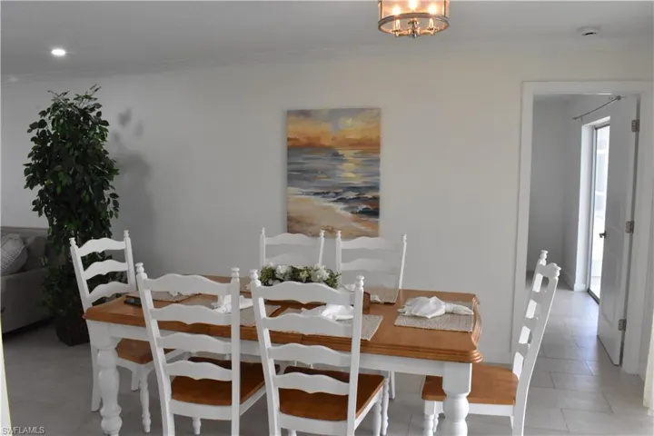 Dining area with ornamental molding, light tile patterned flooring, and a chandelier