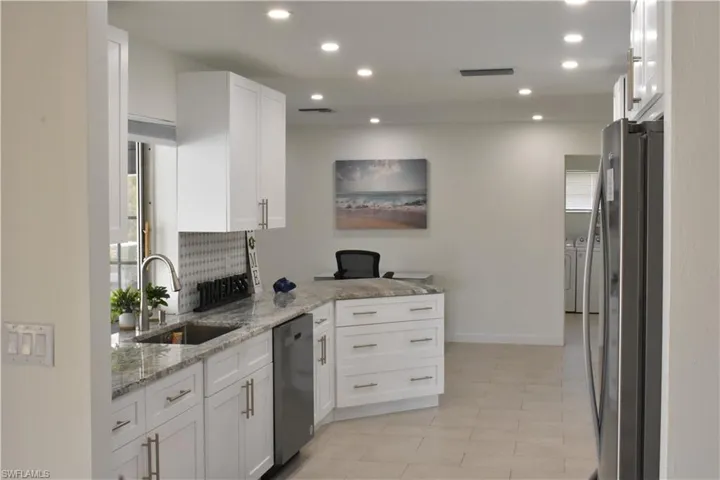 Kitchen with light stone counters, stainless steel appliances, white cabinetry, recessed lighting, and tasteful backsplash