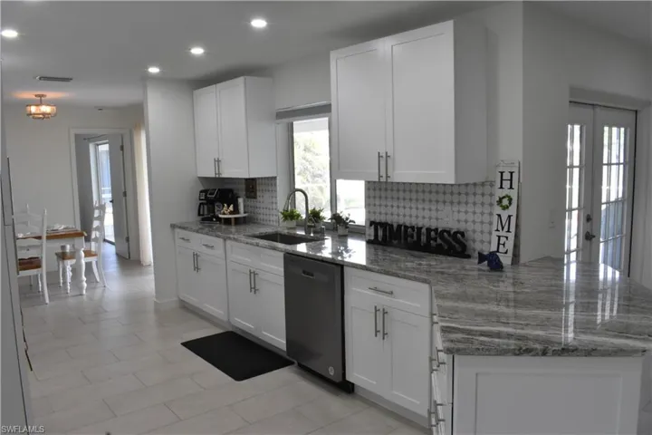 Kitchen featuring light stone countertops, a peninsula, white cabinetry, decorative backsplash, and recessed lighting