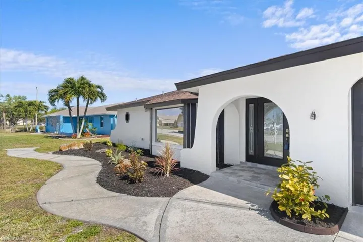 Property entrance with stucco siding and a lawn