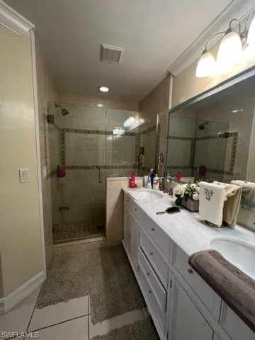 Bathroom with double vanity, a stall shower, and light tile patterned flooring